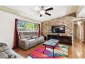 Cozy living room with exposed brick wall, hardwood floors, ceiling fan and plenty of natural light at 422 Dunedin Cir, Temple Terrace, FL 33617