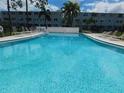 Community pool with clear blue water, surrounded by lounge chairs and palm trees at 4715 Bay Ne St # 119, St Petersburg, FL 33703