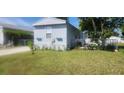 Exterior shot of the manufactured home with green lawn, plants, and fenced area at 5830 Portsmouth Dr, Tampa, FL 33615
