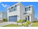 Inviting two-story home with a covered entry, a blue garage door, and professionally landscaped front yard at 636 Sunlit Coral St, Ruskin, FL 33570