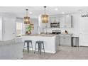 Open kitchen with a spacious island, pendant lighting, modern appliances, and light-gray cabinetry at 636 Sunlit Coral St, Ruskin, FL 33570