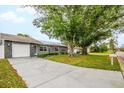 Single-story home featuring a stone-accented garage, solar panels, a well-kept lawn, and a long driveway at 7111 13Th E St, Sarasota, FL 34243