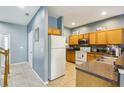 Well-lit kitchen with wooden cabinets, white appliances, and tile flooring at 8125 Stone Path Way, Tampa, FL 33647