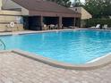 Community pool with clear blue water, plenty of lounge chairs and a covered picnic area at 825 S Village N Dr # 201, St Petersburg, FL 33716