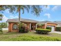 Charming single-story home featuring mature trees, blooming bushes, and an arched window at 8827 Helmsly Ln, Hudson, FL 34667