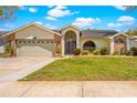 Inviting home with a well-kept lawn, brick accents, arched entryway, and an attached two-car garage at 18836 Green Park Rd, Hudson, FL 34667