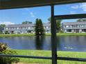 Scenic patio view of a serene pond and lush greenery with other units across the water at 244 Countryside Key Blvd, Oldsmar, FL 34677