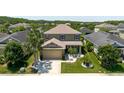 Lovely home with manicured front lawn, contrasted by mature shade trees and lush surrounding foliage at 27094 Carolina Astor, Wesley Chapel, FL 33544