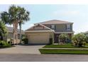 Charming two-story home featuring a well-manicured lawn, palm trees, and an attached two-car garage at 27094 Carolina Astor, Wesley Chapel, FL 33544
