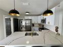 Modern kitchen with stainless steel appliances, marble countertops, stylish pendant lighting, and ample cabinet space at 3910 N Suwanee Ave, Tampa, FL 33603