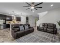 Spacious living room with an open floor plan, dark leather sofas, ceiling fan, and wood-look tile flooring at 4528 Ballantrae Blvd, Land O Lakes, FL 34638
