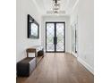 Elegant foyer with hardwood floors, a modern light fixture, and stylish double doors at 5009 W Longfellow Ave, Tampa, FL 33629