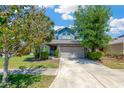 Inviting two-story home featuring a manicured lawn, mature trees, and a two-car garage at 7502 Sea Lilly Ct, Apollo Beach, FL 33572