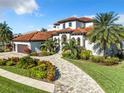Stunning two-story home with a tile roof, lush landscaping, and a brick driveway at 949 Symphony Isles Blvd, Apollo Beach, FL 33572