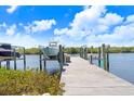 A wooden dock with boat lift surrounded by lush greenery, calm waters, and a sunny sky at 1134 Starfish Ln, Tarpon Springs, FL 34689