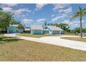 Beautiful light-blue home with large driveway, mature trees, and lush landscaping at 1305 Greenfield Cir, Venice, FL 34292