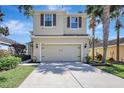 Inviting two-story home with a two car garage, landscaped yard, and mature palm trees at 17419 New Cross Cir, Lithia, FL 33547