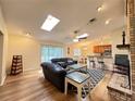 Open-concept living room featuring wood floors, skylights, a fireplace and seamless access to kitchen at 3907 Applegate Cir, Brandon, FL 33511