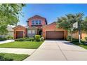 Charming two-story home with a three-car garage, colorful stucco, manicured lawn, and stone accents at 4289 Ortona Ln, Wesley Chapel, FL 33543