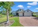 Beautiful curb appeal with a lush green lawn, mature trees, and a brick driveway at 5518 72Nd E Ter, Ellenton, FL 34222