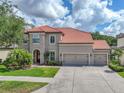 Inviting two-story home with a tile roof, arched entryway, and a spacious three-car garage at 7927 Hampton Lake Dr, Tampa, FL 33647