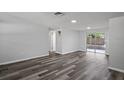 Spacious living room featuring modern gray flooring, freshly painted walls, and sliding glass doors to the backyard at 8733 Goshen Ln, Port Richey, FL 34668