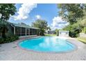Backyard with a private pool, screened-in lanai, brick patio, and mature trees at 10907 Kewanee Dr, Temple Terrace, FL 33617
