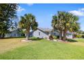 Corner lot shows the home exterior and side yard with large shade trees and landscaping at 13528 Woodside Dr, Hudson, FL 34667