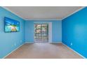 Bright living room with blue walls, light carpet, and a sliding door to the patio at 200 Glennes Ln # 205, Dunedin, FL 34698