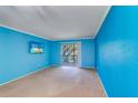 Bright living room with blue walls, light carpet, and a sliding door to the patio at 200 Glennes Ln # 205, Dunedin, FL 34698