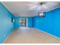 Bright living room features blue walls, light carpet, and a sliding door at 200 Glennes Ln # 205, Dunedin, FL 34698