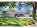 Charming home with a well-manicured lawn, mature trees, and a welcoming red front door at 2671 Clubhouse N Dr, Clearwater, FL 33761