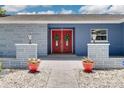 Inviting front entrance with double red doors, tasteful landscaping, and decorative flower pots at 2671 Clubhouse N Dr, Clearwater, FL 33761