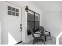 Cozy front porch featuring two chairs, patterned tile, and a bright white door with a grid window at 3512 Haines N Rd, St Petersburg, FL 33704