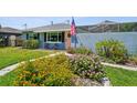 Blue house with vibrant flowers, an American flag, manicured lawn, and screened in porch in the back at 4013 W Waterman Ave, Tampa, FL 33609