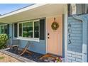 Cozy front porch with seating, charming wreath on the pink door, and a view of lush surroundings at 4013 W Waterman Ave, Tampa, FL 33609