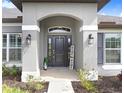 Inviting front entry with decorative pillars, modern lighting, and a charming welcome sign at 41043 Stanton Hall Dr, Dade City, FL 33525