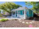 Charming turquoise home with a welcoming white-railed front porch and manicured landscaping, offering curb appeal at 56 W Park St, Tarpon Springs, FL 34689