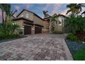 A luxurious home boasting a paver driveway, three-car garage, and lush tropical landscaping at 6315 Marbella Blvd, Apollo Beach, FL 33572