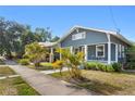 Charming home with a cozy front porch, red door, mature landscaping, and blue siding under a clear blue sky at 107 W Amelia Ave, Tampa, FL 33602