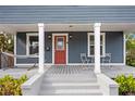 Inviting front porch with a hammock, chairs, and a vibrant red door at 107 W Amelia Ave, Tampa, FL 33602