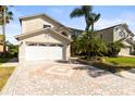Beautiful home featuring a two-car garage, lush landscaping, and a brick paver driveway at 11503 Whispering Hollow Dr, Tampa, FL 33635