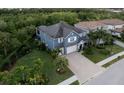 Aerial view of a beautiful blue home with a brick driveway surrounded by lush greenery at 12026 Medley Ter, Lakewood Ranch, FL 34211