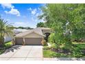 Charming home featuring a three-car garage, well-maintained landscaping, and a concrete driveway at 16118 Lytham Dr, Odessa, FL 33556