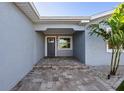 Covered front entry with paver steps and a freshly painted front door at 17730 Long Point Dr, Redington Shores, FL 33708