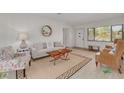 Bright living room featuring a cozy couch, floral chair, wooden coffee table, and natural light from the front window at 225 Cevera Dr, Dunedin, FL 34698