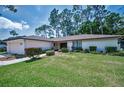 Single-story home with a well-manicured lawn, trimmed shrubs, and paver walkway at 2486 Indian E Trl, Palm Harbor, FL 34683