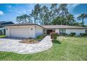 Beautiful single-story home with a paved driveway, manicured lawn, and vibrant shrubs at 2486 Indian E Trl, Palm Harbor, FL 34683