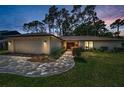 Charming home featuring a brick driveway, manicured lawn, and lush landscaping at dusk at 2486 Indian E Trl, Palm Harbor, FL 34683
