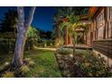 Beautifully landscaped yard with manicured hedges, palm trees, and exterior lighting highlighting a home at 2536 Burlington N Ave, St Petersburg, FL 33713